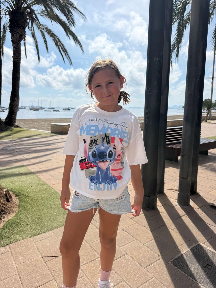 Olivia, Brett and Rachael’s daughter, smiling on a seafront promenade lined with palm trees.